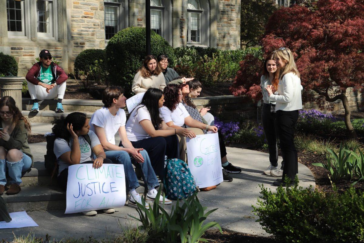 Wide angled photo of students sitting with St. Joe’s President Cheryl A. McConnell, who is speaking to the students holding signs in protest