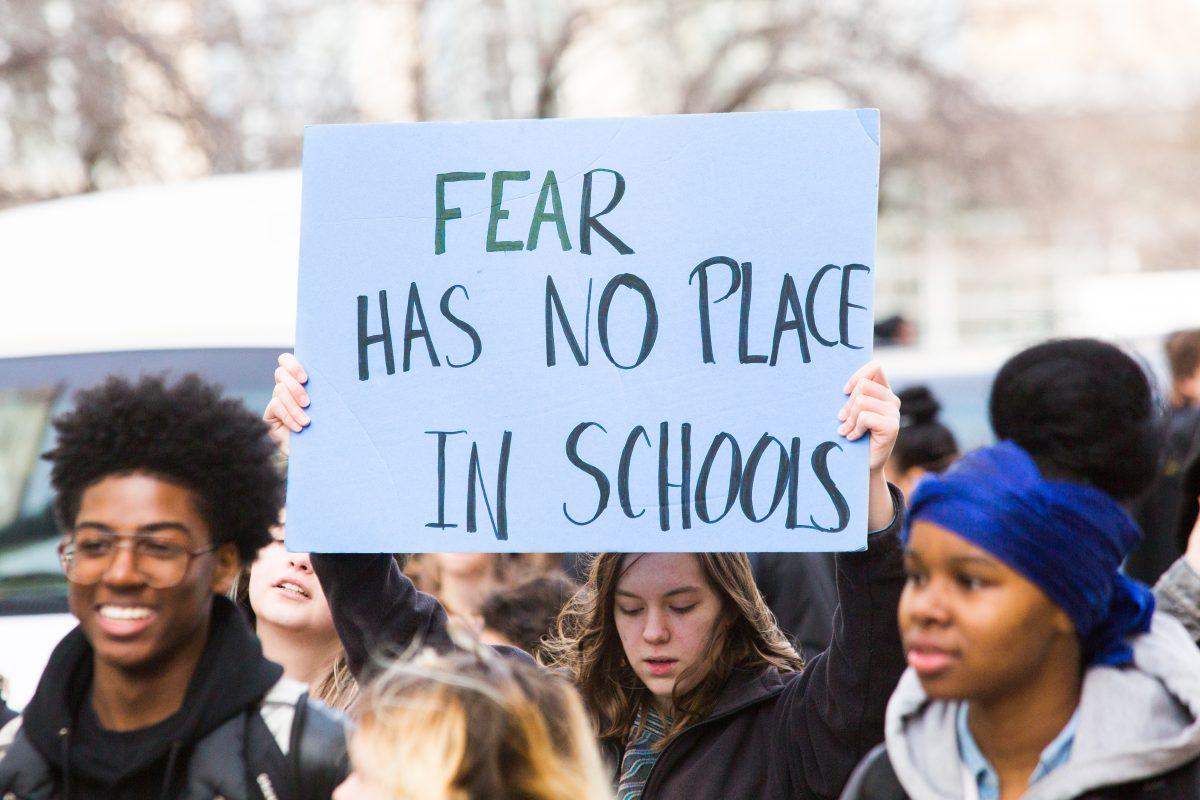 A student holds a sign during a walkout in Center City (Photo by Luke Malanga 20).