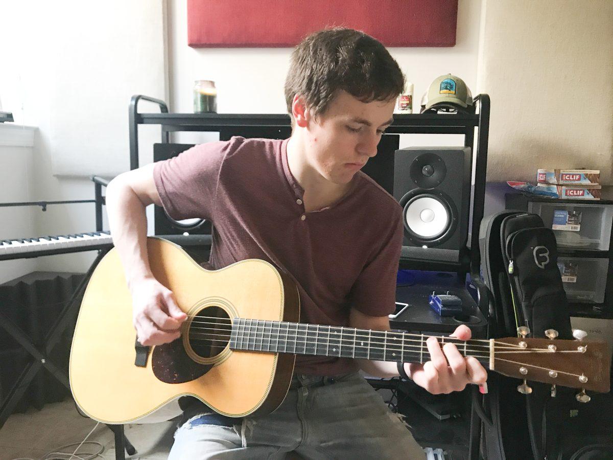 Andrew Babin ’19 plays his acoustic guitar in his home studio (Photo by Rebecca Barus ’19).
