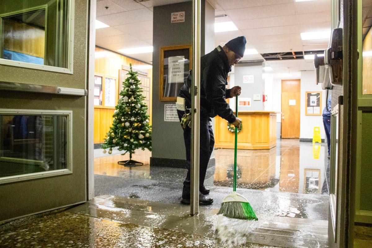 A Public Safety officer sweeps water out of the lobby of LaFarge Residence Center. PHOTO: MITCHELL SHIELDS 22/THE HAWK