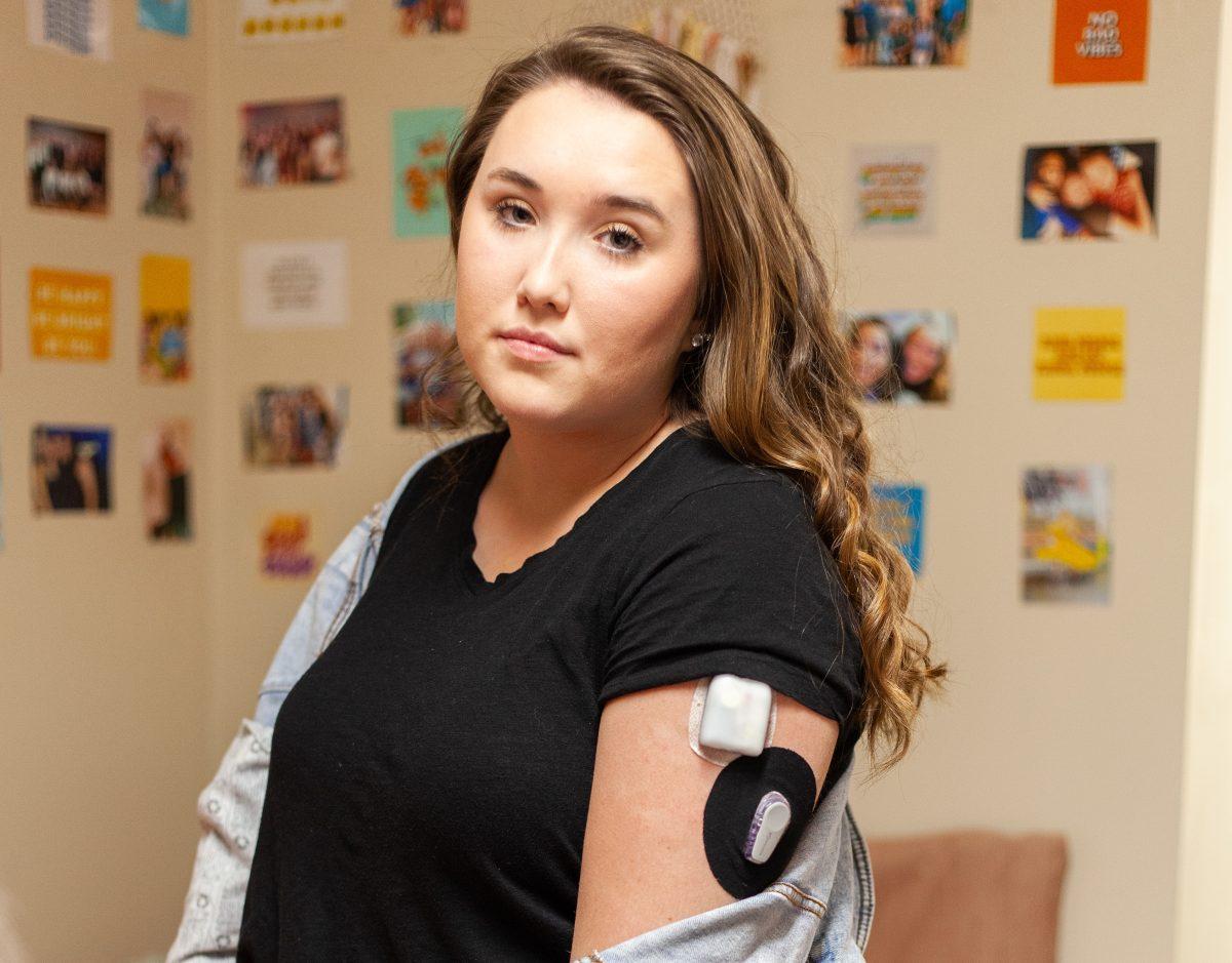 Emily Fordham ’21 stands in her room and displays her Continuous Glucose Monitoring System and insulin pump system. PHOTO: MITCHELL SHIELDS ’22/THE HAWK