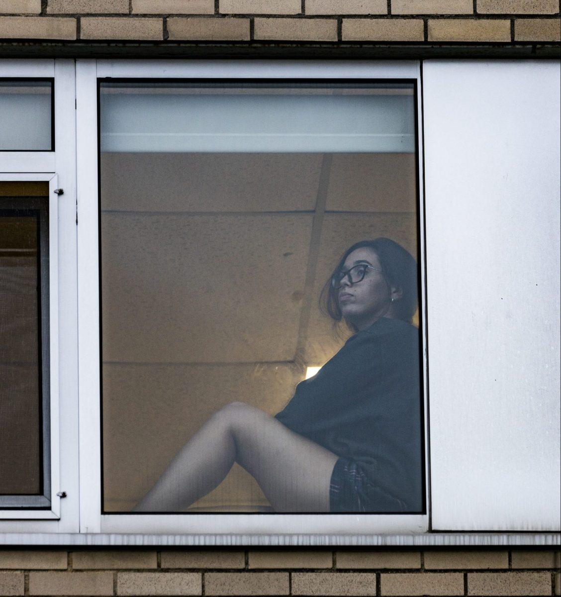 Katerina Calvo ’24 looks out from her window in Moore Hall, where she isolated. PHOTO: MITCHELL SHIELDS ’22/THE HAWK
