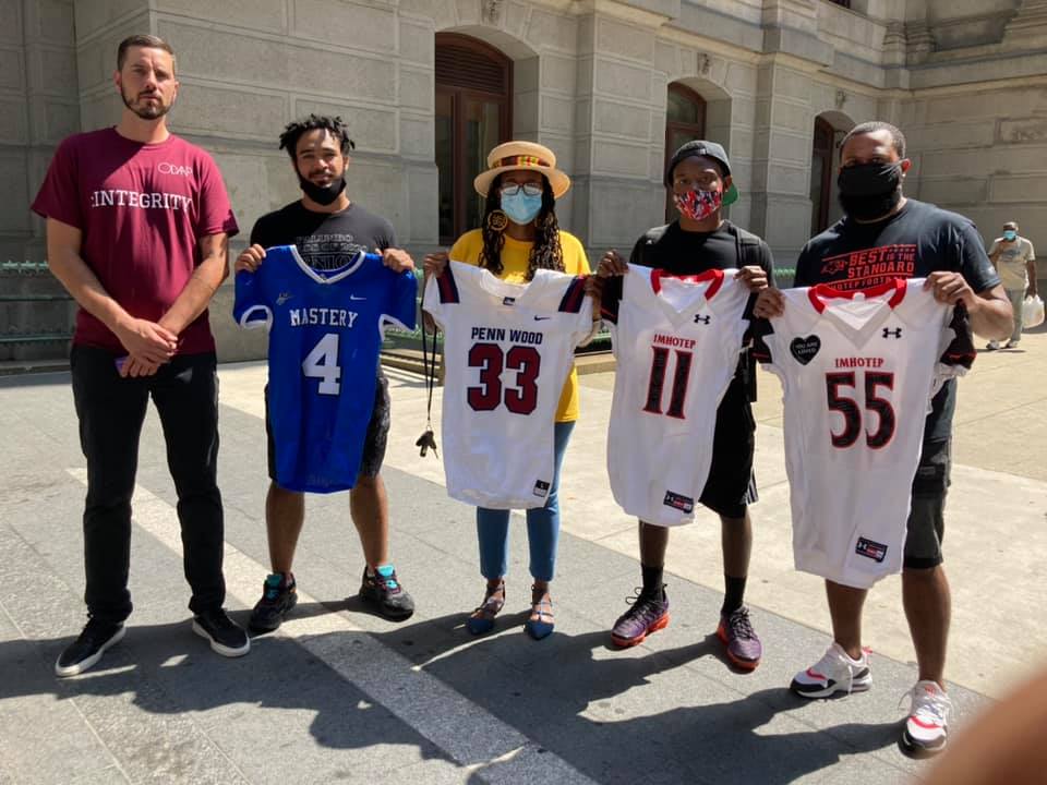 Valencia Peterson and KeShan Allen (third and fourth from left respectively) stand outside of City Hall with jerseys
representing players that were victims of gun violence. PHOTO COURTESY OF VALENCIA PETERSON