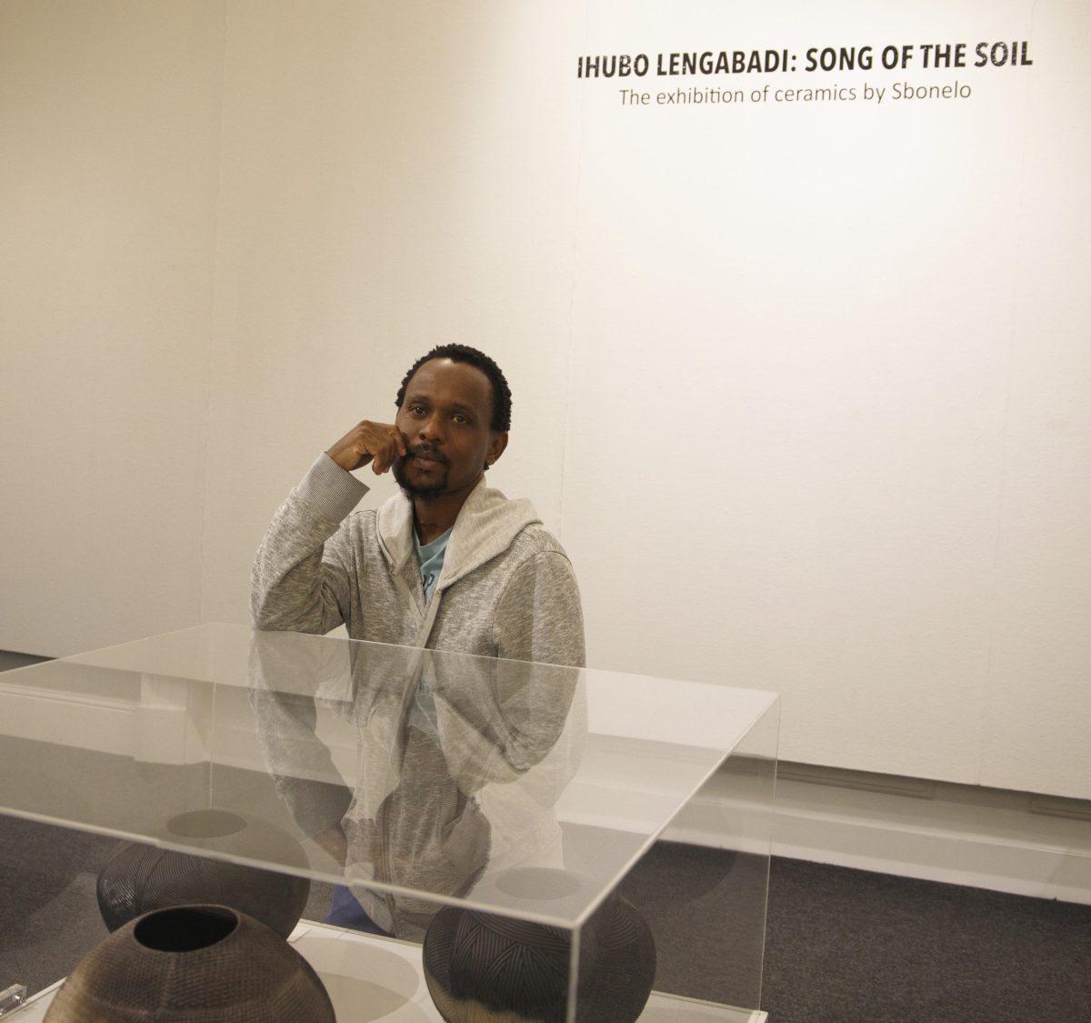 S’bonelo Tau Luthuli, a contemporary traditional ceramicist, stands next to some of his work exhibited at Tatham Art Gallery in Pietermaritzburg, KwaZulu-Natal. PHOTO: ALLIE MILLER '24/THE HAWK