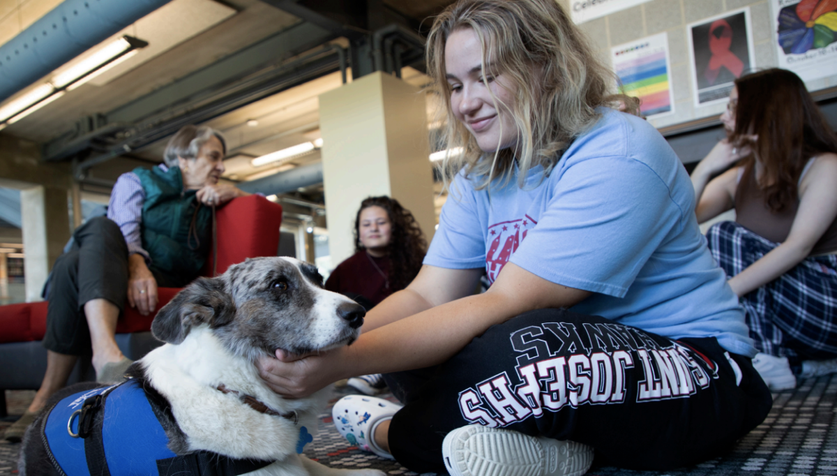 Tess Margis ’24 with a dog from the therapy dog session in the Post Learning Commons. PHOTO: KELLY SHANNON ’24/THE HAWK