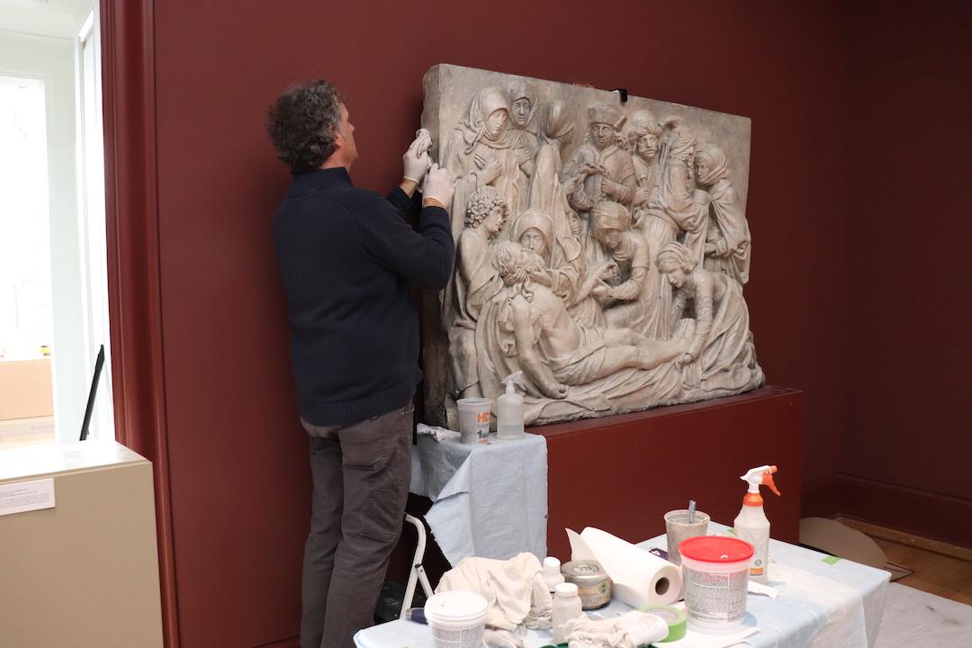 Douglas Martenson carefully cleaning the plaster artwork with a
rag and water. PHOTO: ALLIE MILLER 24/THE HAWK