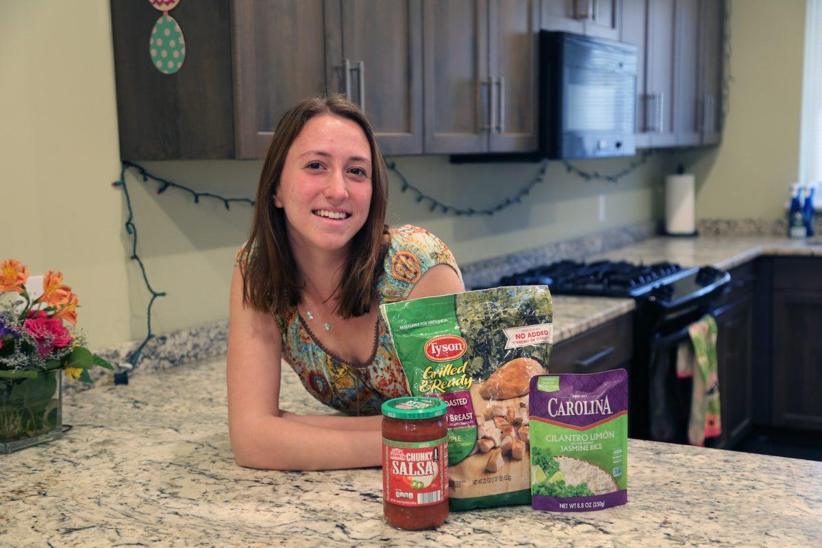 Hannah Madeya posing at her kitchen counter with with ingredients she used as part of her attempt to try three-ingredient meals for a week