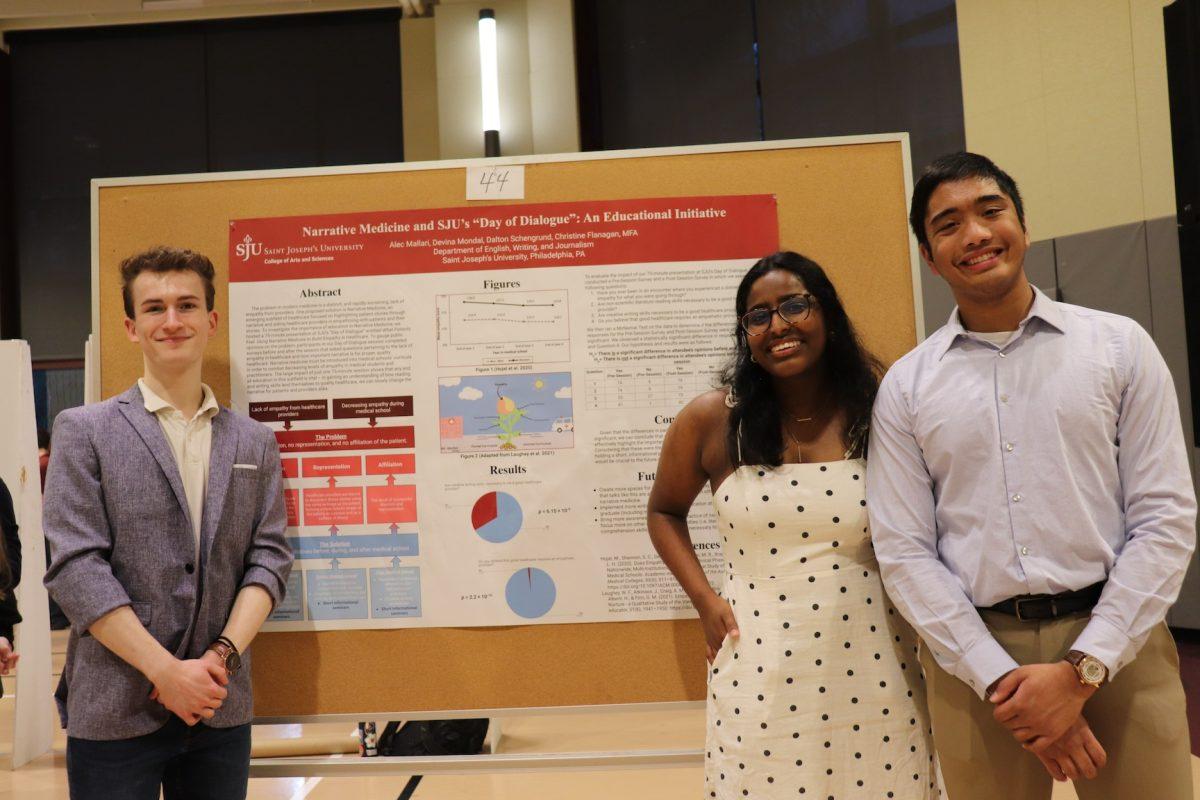 Dalton Schengrund 25, Devina Mondal 25, and Alec Mallari standing in front of a poster, which says Narrative Medicine and SJUs Day of Dialogue: An Educational Initiative.