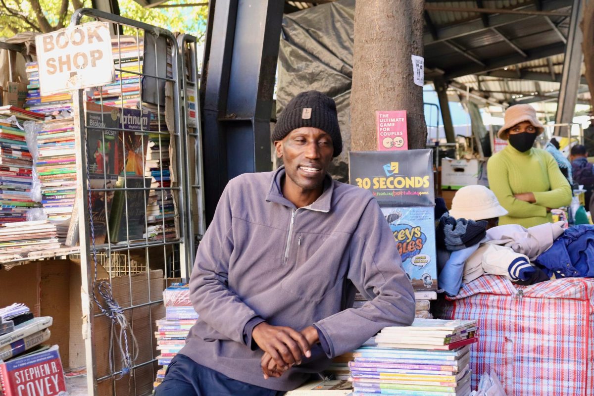 Bookseller Henry Mugo says he loves selling books because it allows him to talk about literary works with customers at his book stand in central Johannesburg. PHOTO: ZACH PODOLNICK ’26/THE HAWK 