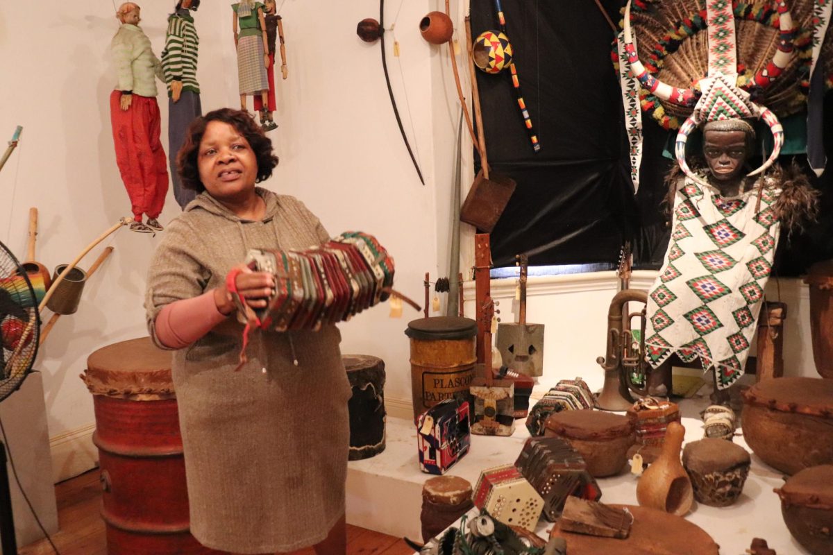 Phumzile Nkosi, curator and manager of the Phansi Museum, plays an accordion, one of many musical instruments in the museum's collection. PHOTO: LILLI DELLHEIM, M.A. '25/THE HAWK