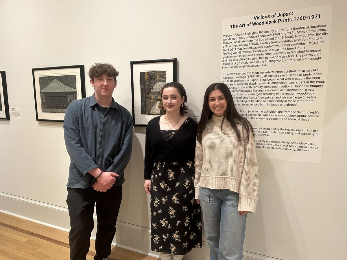 Joey Kowal '27, Shannon Tonetta '26, and Mary LaRosa '25 pose next to the signage for am exhibit featuring Japanese woodblock prints from the late 18th century through the 20th century, was curated by students in the Curating an Exhibition course. PHOTO GRACE O'MEARA '27. 