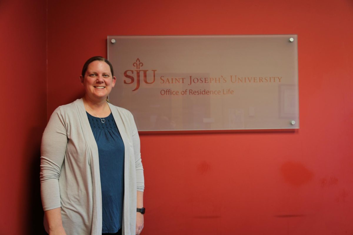 Kelly Bersett, director of Residence Life at St. Joe’s, poses in front of the Office of Residence Life sign, located in LaFarge Hall, Jan. 27. PHOTO: MADELINE WILLIAMS ’26/THE HAWK