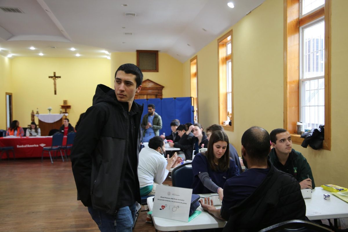 Fredy Abboud ’26 works inside Mother of Mercy House while a patron has their blood pressure taken,
Feb. 8. PHOTO: ZACH PODOLNICK ’26/THE HAWK