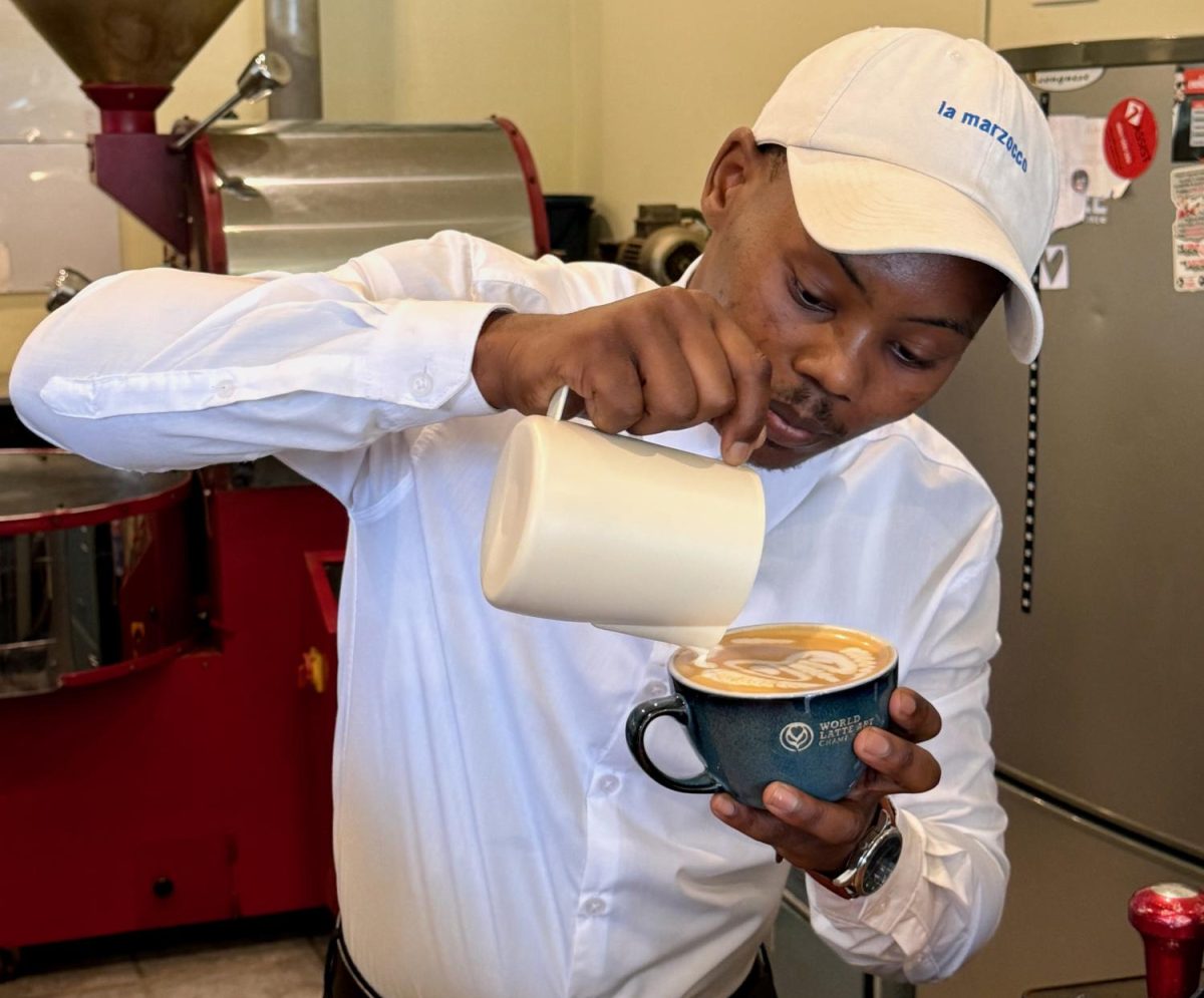 Latte art champion Vincent Majola pours steamed milk into a cup of coffee at The Bean Green Coffee Roastery where he has begun training aspiring baristas in the craft of coffee design. PHOTO: HELENA SIMS/THE HAWK 
