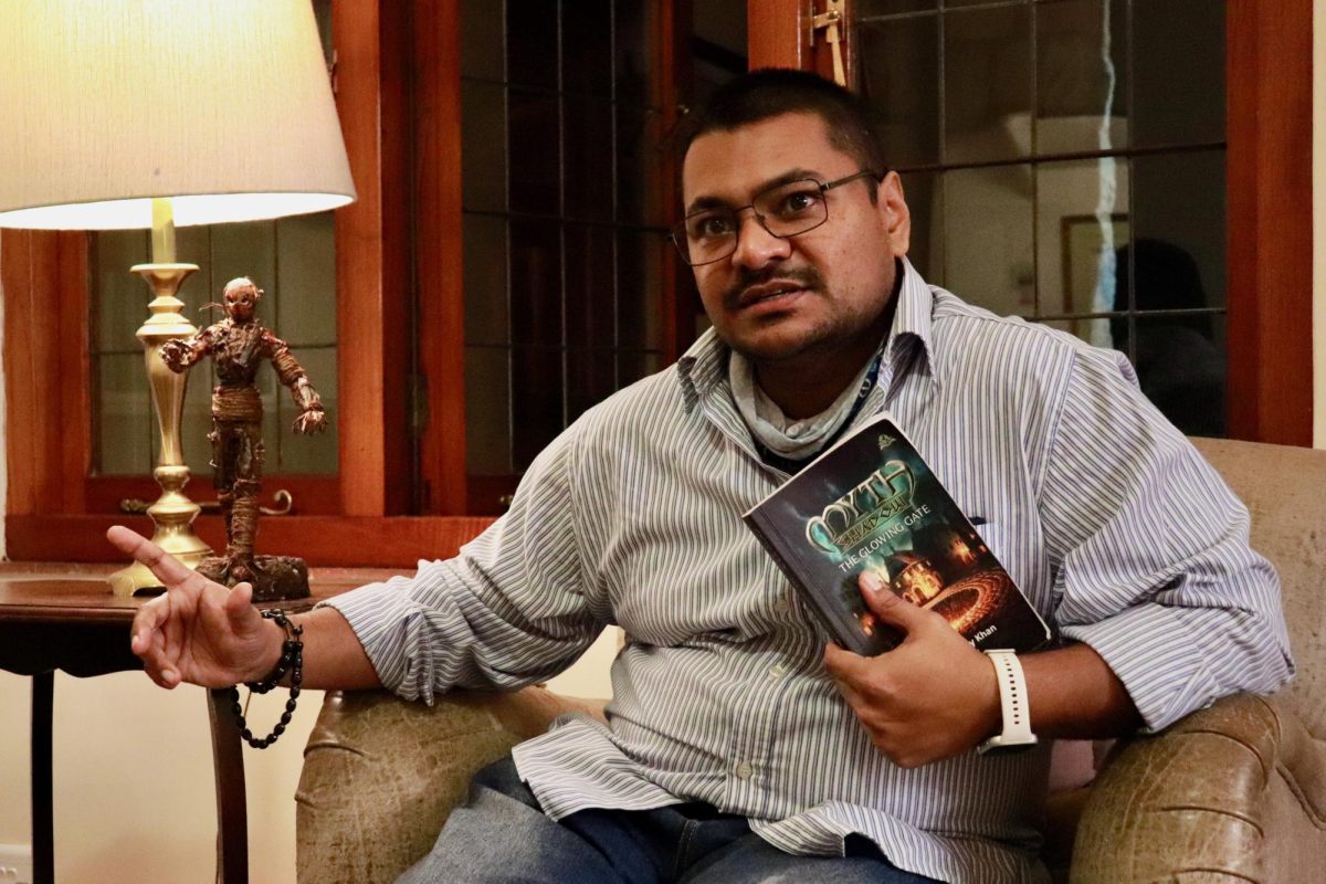 Ziyaad Ally sits next to a homemade figurine of Reigus, a character in his fantasy novel, “Myth Shadow: The Glowing Gate,” that he constructed with his daughter. In the book, Reigus serves as an introductory challenge to the main character, Cassandra. PHOTO: MAXIMILIAN MURPHY/THE HAWK
