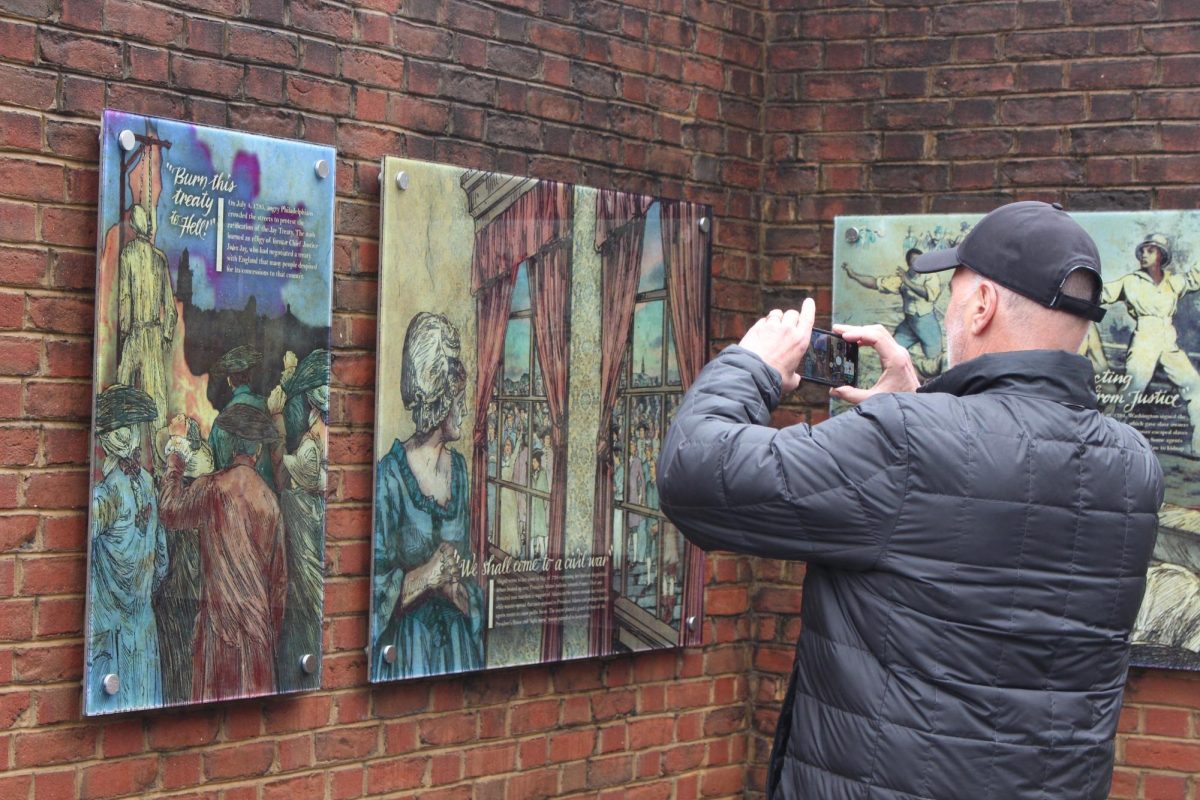 A visitor takes a picture of reinstalled plaques at the President’s House Feb. 20. PHOTO: LUKE SANELLI ’26/THE HAWK
