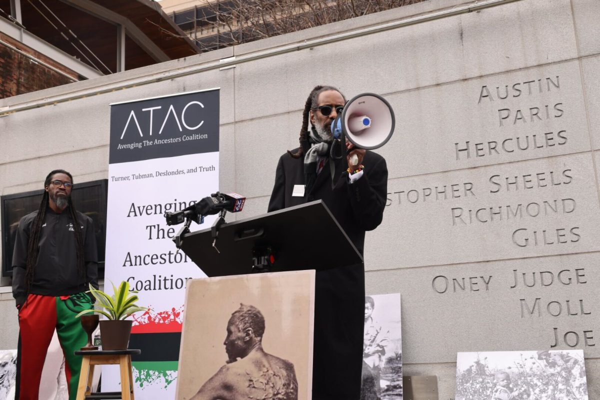 Michael Coard, co-founder of Avenge The Ancestors Coalition, announces the judicial ruling that the federal government must reinstate displays commemorating the nine enslaved Africans owned by George Washington at his Philadelphia house. News of the U.S. District Court’s ruling came during the ATAC’s rally at The President House’s Memorial. PHOTOS: SAHR KARIMU ’26/THE HAWK